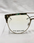 Close-up view of a pair of eyeglasses. The Frosty frame by For Art's Sake® features an electric green marble acetate design with green and brown shades. The left lens has the text "For Art's Sake" printed at the bottom. White jade gemstone nose pads complete this stylish look against a smooth white background.