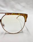 Close-up of the right half of a pair of fashion-forward glasses known as Frosty by For Art's Sake®. The frame boasts a unique design, blending transparent brown and yellow tortoiseshell along the top edge, transitioning into an electric green marble acetate structure for a chic and modern look.