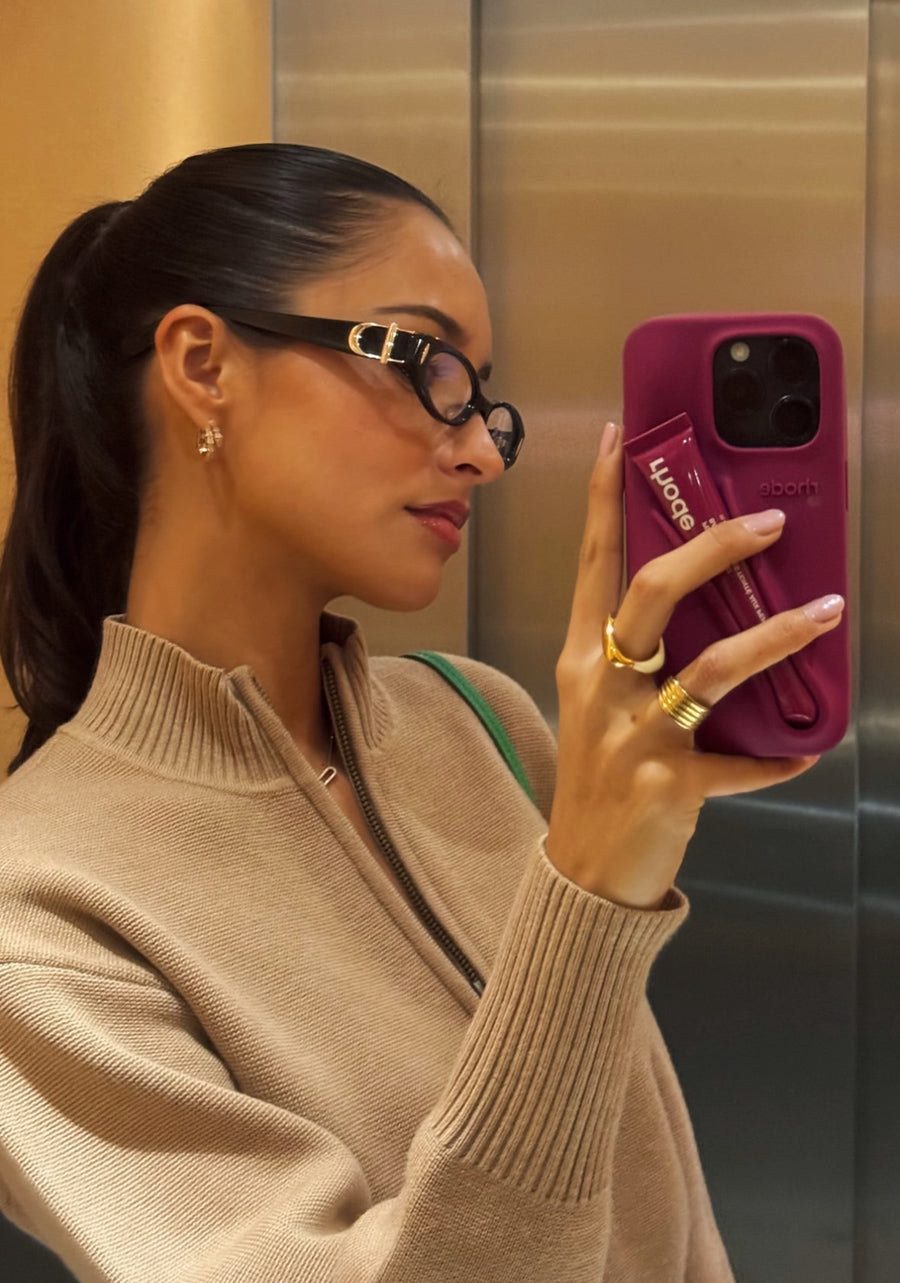 Alexandra Saint Mleux in designer For Art’s Sake Cigar clear glasses, serving a relaxed off-duty casual look. Sporting Rhodes phone case