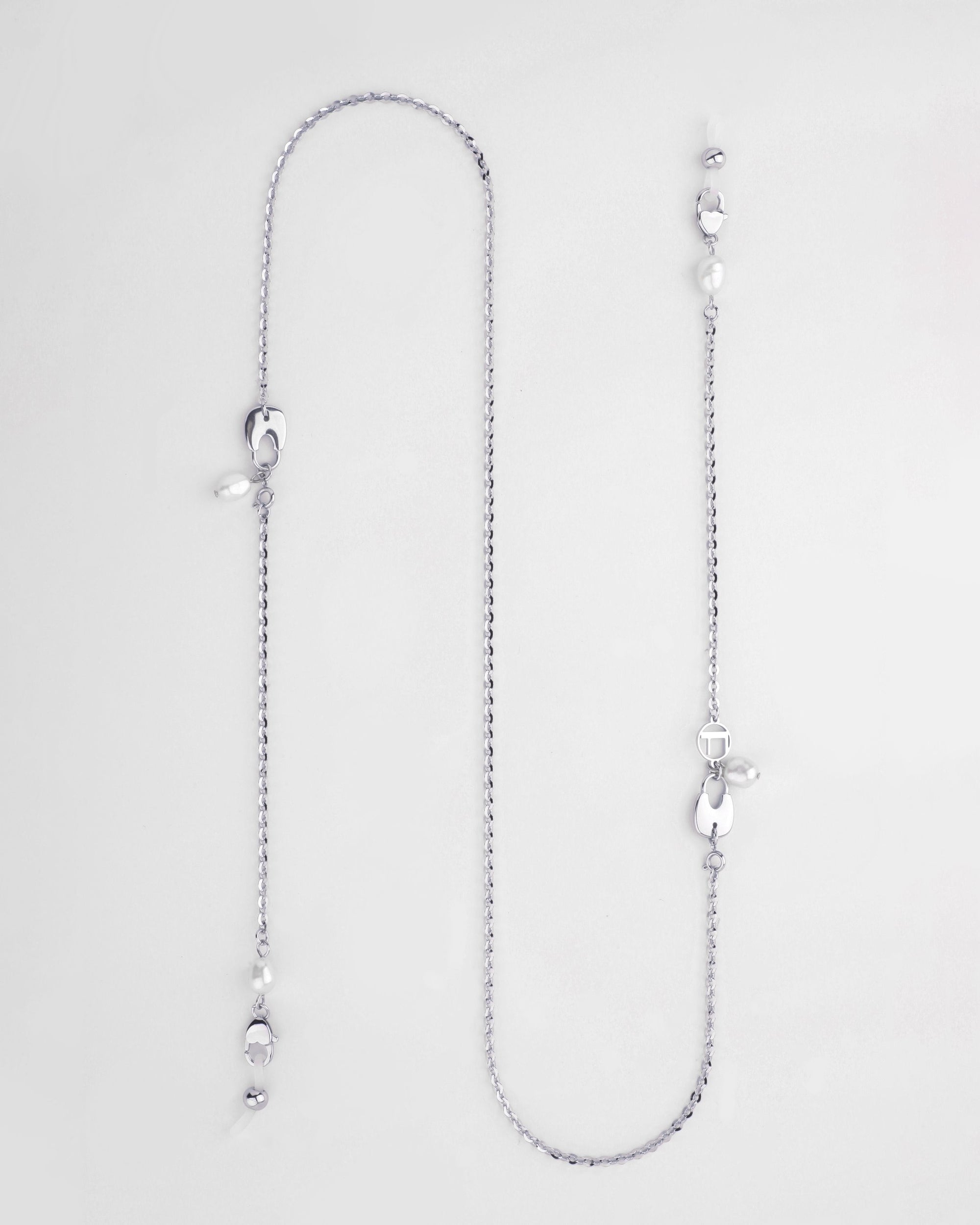 A long silver Belgravia Glasses Chain with an intricate chain design, featuring a mix of small, round beads and larger, irregularly shaped pearls. Freshwater pearl drops are spaced along the chain, giving the glasses chain a delicate and elegant look. The background is plain and white. Available from For Art's Sake®.