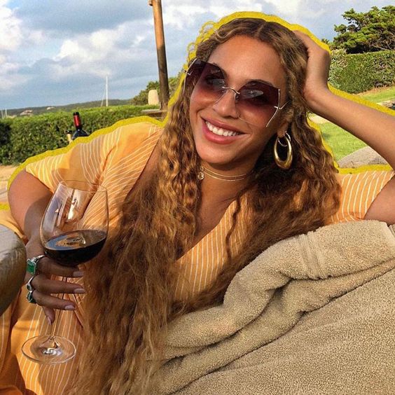 Beyoncé on vacation channeling golden goddess vibes in designer For Art’s Sake Generation sunglasses.