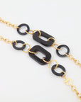 A fashionable NYC Glasses Chain featuring alternating black geometric links and 18-karat gold-plated chain links, creating a bold and stylish accessory. The black acetate links, in a mix of rectangular and circular shapes, are connected by smaller gold loop links. The overall For Art's Sake® aesthetic is modern and chic.