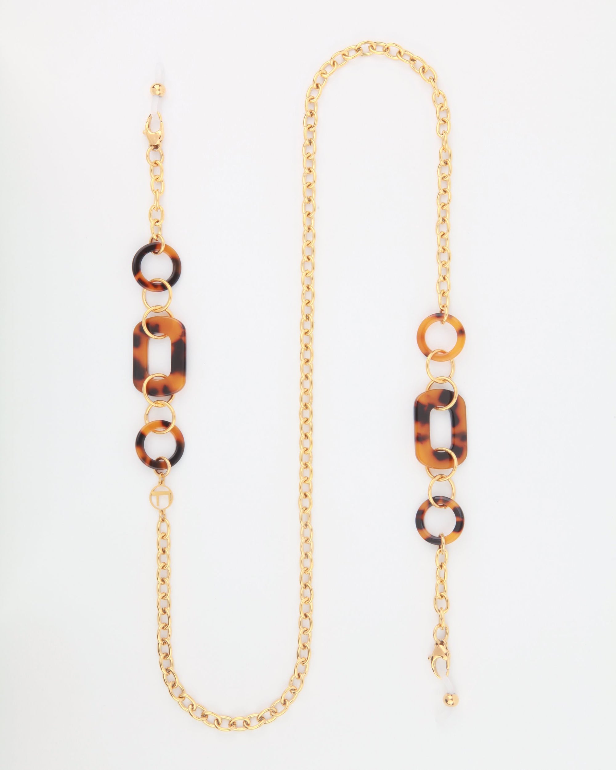 18-karat gold-plated eyeglass chain with oversized acetate links and interspersed brown tortoise shell-like rings. The For Art's Sake® NYC Glasses Chain features a lobster clasp at one end and adjustable loops at the other for attaching to glasses. The overall appearance is stylish and functional.