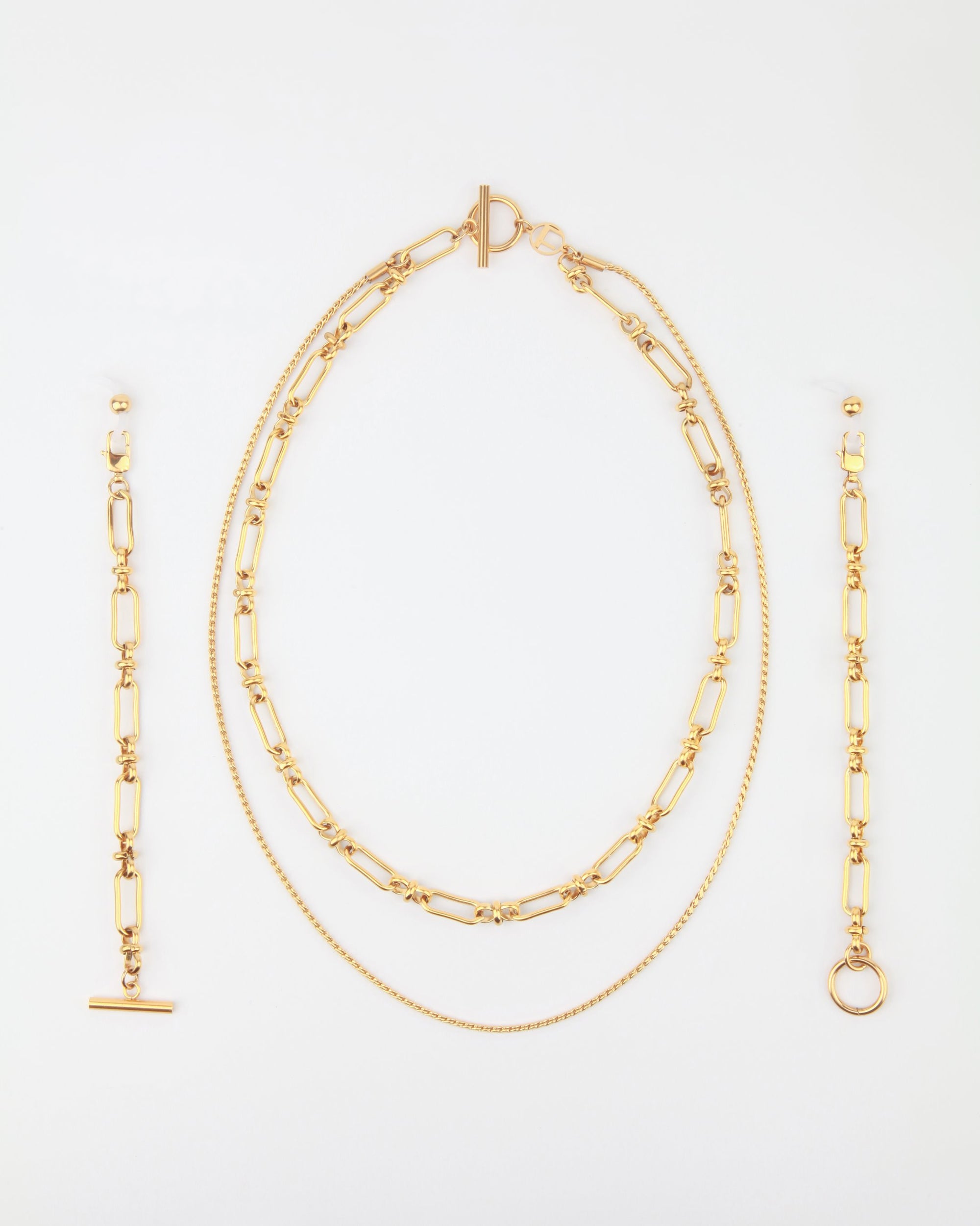 A Vienna Glasses Chain by For Art's Sake® against a white background, including a pair of dangling earrings, an 18-karat gold-plating layered necklace with both a chain and a linked design, and a bracelet featuring a similar linked pattern. The pieces are neatly arranged in a vertical orientation.