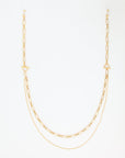 A delicate Vienna Glasses Chain is displayed against a plain white background. The 18-karat gold-plated piece by For Art's Sake® features two types of chains: one with elongated oval links and the other a smooth, fine chain, creating a layered effect. The clasp is a T-bar style.