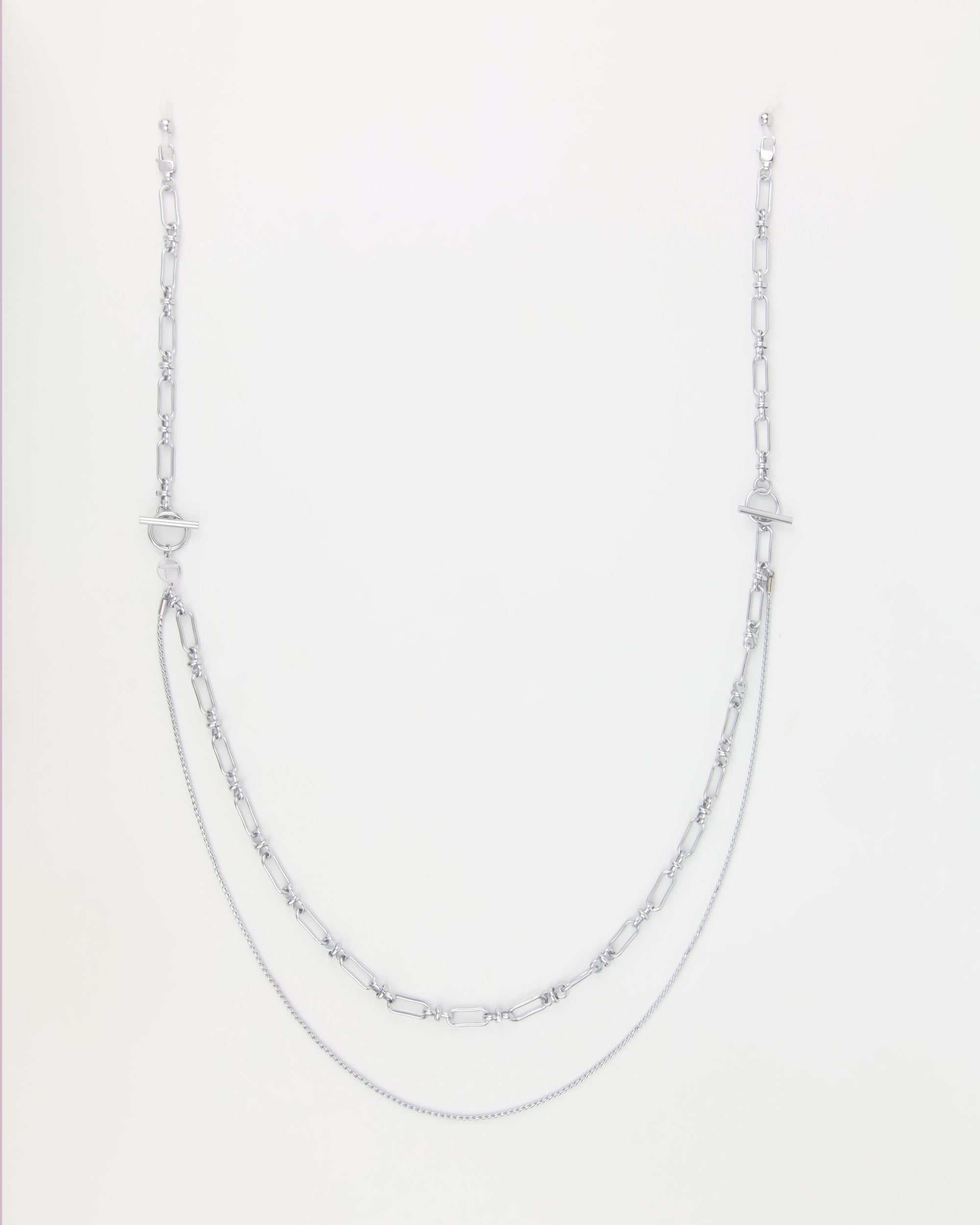 A silver necklace with a unique design featuring two types of chain styles: a thin, delicate chain at the lower level and a thicker, patterned chain on top. Enhanced with 18-karat gold-plating, this layered accessory exudes style and elegance, perfect for pairing with the Vienna Glasses Chain by For Art's Sake®.