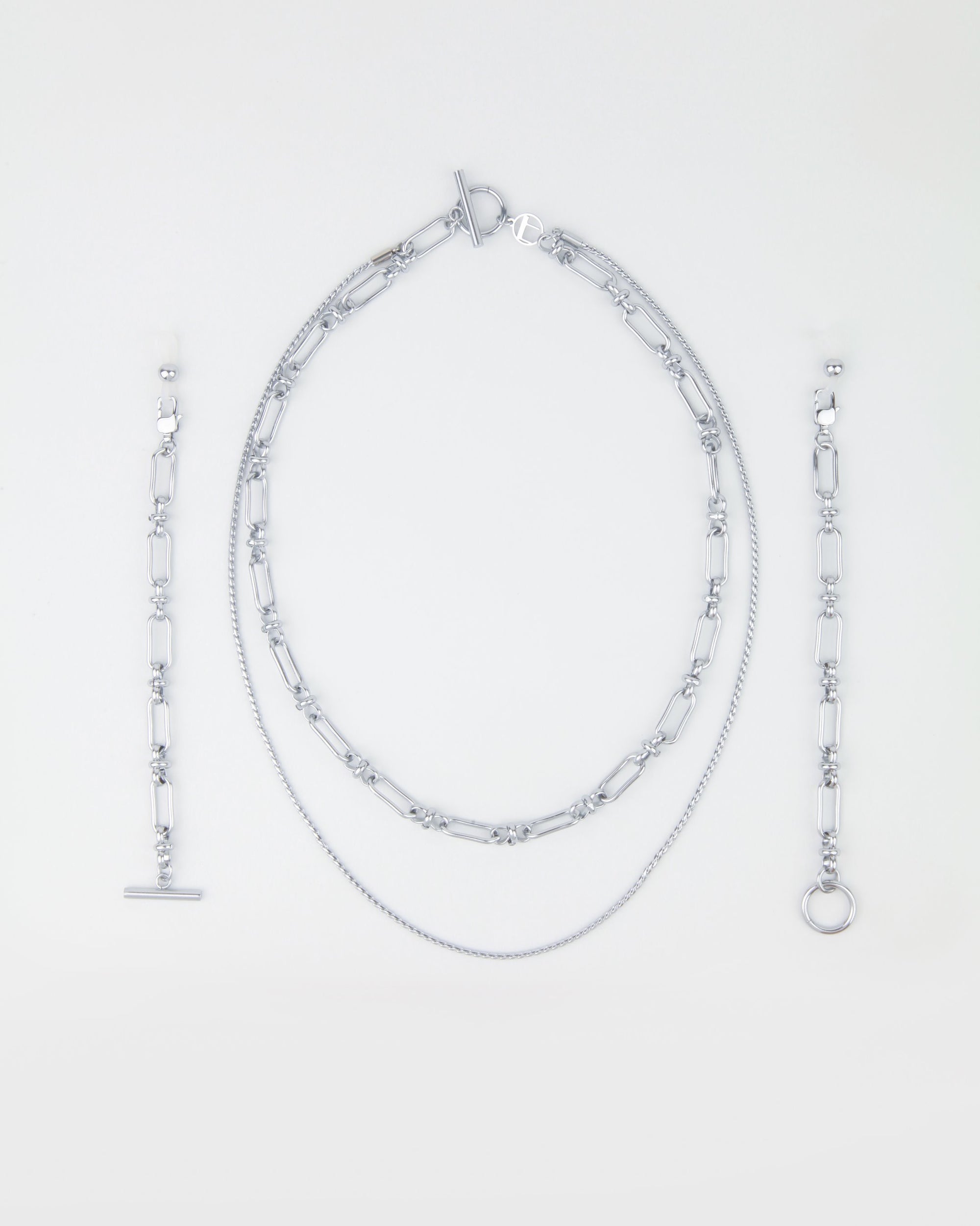 A Vienna Glasses Chain by For Art's Sake®, featuring an oval link necklace with a toggle clasp, a shorter fine chain necklace, a bracelet with a toggle clasp, and a bracelet with a ring clasp—all arranged neatly on a light background. The collection's 18-karat gold-plating adds an elegant touch to each piece.