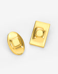 The Geometry Earrings by For Art's Sake®: a shiny gold oval earring with a raised square center and a shiny gold rectangular earring with a raised circular center, both displayed on a white background.