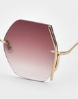 Close-up of For Art's Sake® Generation sunglasses: geometric hexagonal frames in thin gold metal, jadestone nosepads, pink gradient lenses, and essential UV protection—all showcased against a plain white background.