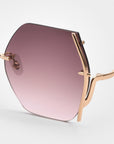 Close-up of For Art's Sake® Generation sunglasses showing a single hexagonal lens with UV protection, a pink-to-purple gradient tint, and slim gold wavy arms, set against a plain white background.