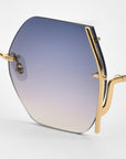 Close-up of For Art's Sake® Generation Topaz sunglasses—ONLY 1 AVAILABLE—with octagonal blue-to-clear gradient lenses and a gold, branch-like frame. A rare find for standout style and reliable UV protection.
