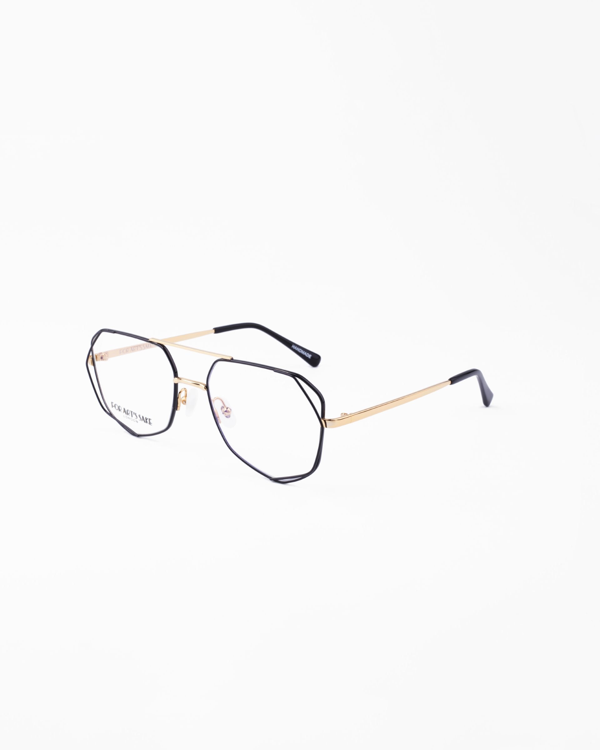 A pair of stylish Genius Two eyeglasses by For Art's Sake® with thin gold metal frames and black temple tips against a plain white background. The hexagonal lenses, equipped with a blue light filter, offer a modern and chic look while providing essential eye protection.