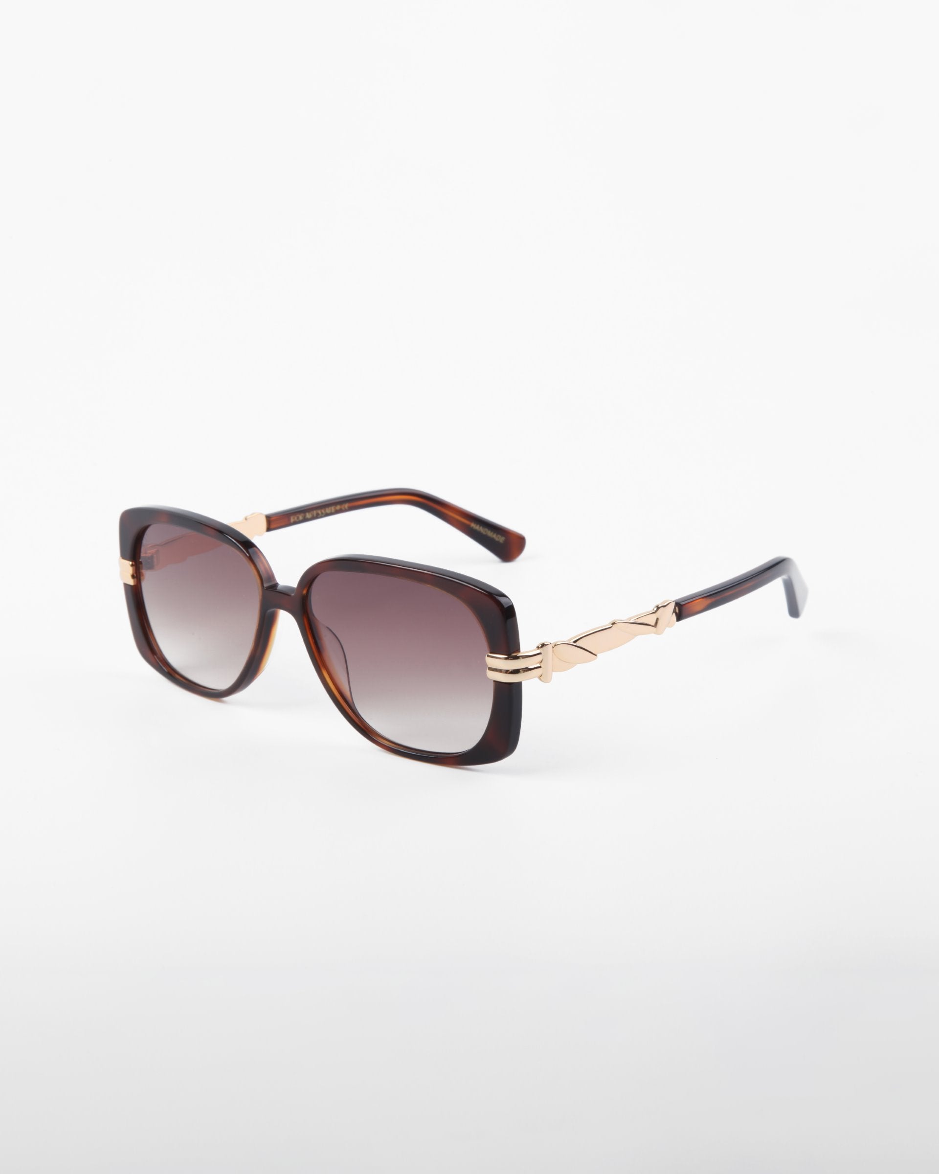 For Art's Sake® presents the Icon- ARC sunglasses, featuring square UVA & UVB-protected lenses with a dark tint. The modern elegance shines through with a dark tortoiseshell frame and gold temple accents, crafted from handmade acetate and displayed on a white background.