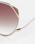 Close-up of For Art's Sake® Wonderland sunglasses featuring a gold geometric frame, gradient brown lenses, jadestone nose pads, and 100% UV protection against a plain white background.