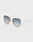 The Wonderland sunglasses by For Art's Sake® feature gold metal frames, jadestone nose pads, and gradient blue lenses with 100% UV protection, shown against a light gray background.