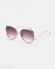 The Wonderland by For Art's Sake® are oversized cat-eye sunglasses with rose gold metal frames, jadestone nose pads, gradient purple lenses offering 100% UV protection, shown on a plain white background.