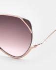 Close-up of the upper half of For Art's Sake® Wonderland handmade rose gold sunglasses featuring large, rounded, pink-tinted gradient lenses with UV protection against a plain light background.