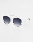 For Art’s Sake® Wonderland sunglasses feature a modern silver frame, jadestone nose pads, thin curved temples, and dark gradient lenses that offer 100% UV protection—all resting elegantly on a white surface.