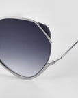 Close-up of For Art’s Sake® Wonderland silver metal-framed sunglasses, featuring jadestone nose pads and dark gradient lenses with 100% UV protection. Image highlights the lens and slim arm against a white background.