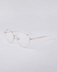 The Millie eyeglasses by For Art's Sake® are a pair of lightweight, rimless frames featuring thin, metallic gold temples and nose pads, strengthened with a stainless steel core for added durability, beautifully showcased against a neutral background.