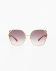 A pair of large, octagonal sunglasses with a gold-plated stainless steel frame and ultra-lightweight nylon lenses that transition from dark at the top to lighter at the bottom. The red-armed Montage by For Art's Sake® offer 100% UVA & UVB protection. The background is plain white.
