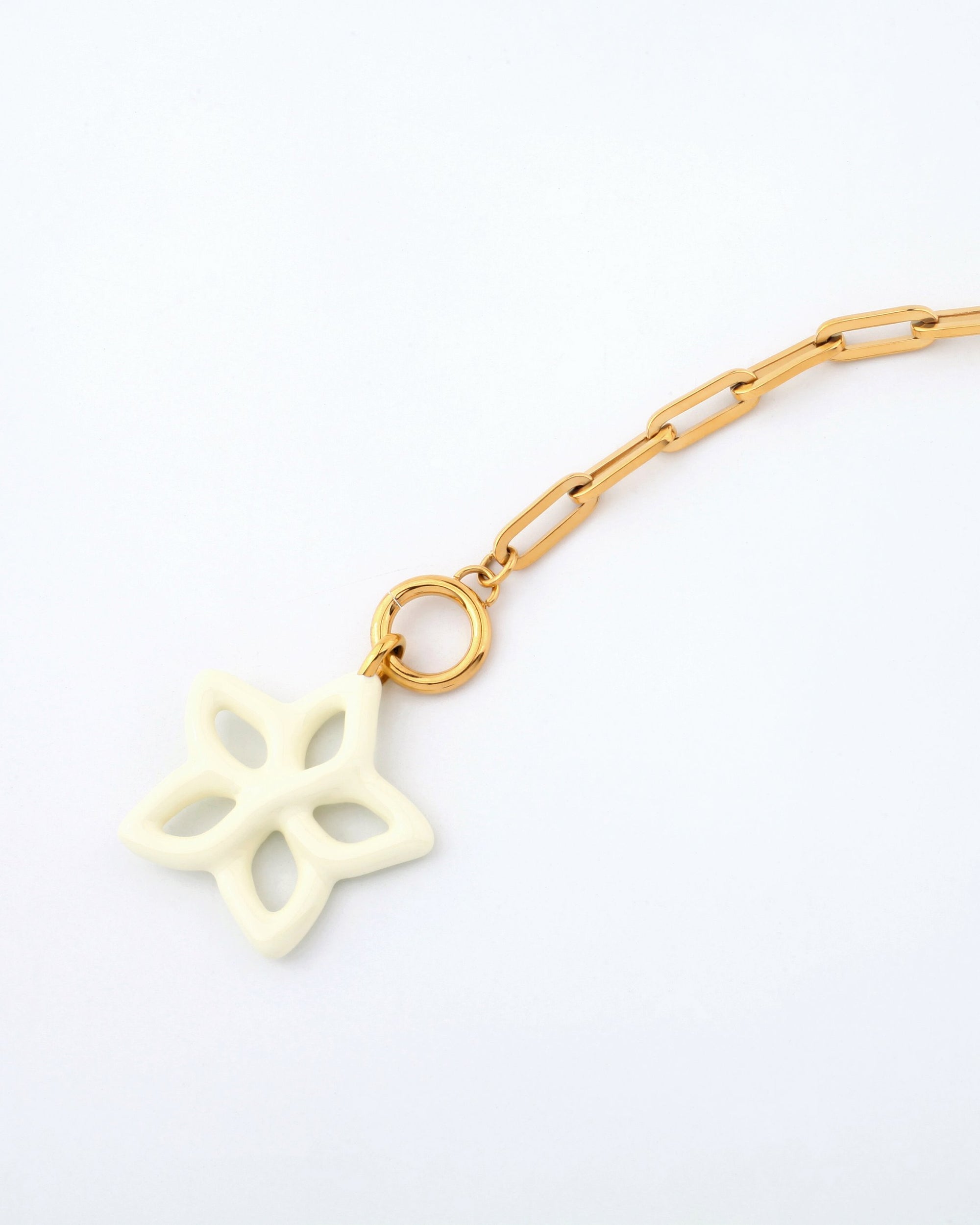 A close-up of the For Art's Sake® Plumeria Necklace, a 49cm gold chain with rectangular links, featuring a unique off-white charm shaped like a stylized, open-petaled flower. The charm is attached to the chain by a gold loop. The background is plain white.