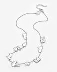 The Forms Necklace by For Art's Sake® showcases abstract, irregular metal shapes spaced along a fine chain with an adjustable clasp, presented on a plain white background.