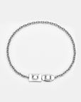 The Geometry Necklace by For Art's Sake® is a silver chain with round links, geometric charms, and a modern rectangular and oval front clasp, shown on a plain light gray background.