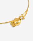 The Rose Choker by For Art’s Sake® showcases a detailed rose-shaped gold pendant on a sleek curved band, captured up close against a plain white background.