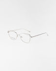 The Twist eyeglasses by For Art's Sake® feature thin, angular silver stainless steel frames and minimalist arms. With clear lenses and optional blue light filter, these modern glasses provide a lightweight, stylish look on any surface.