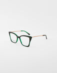A pair of dark green cat-eye eyeglasses with gold-toned metal temples, featuring clear lenses and a glossy finish. These stylish Dion glasses by For Art's Sake®, enhanced with blue light filter lenses, are photographed against a plain white background.
