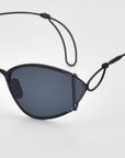 Close-up of For Art's Sake® Ornate sunglasses: vintage-style black frames with dark almond-shaped lenses and distinctive metal wire loops on the temples, shown against a plain white background.
