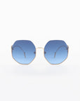 A pair of For Art's Sake® Palace UVA & UVB-protected sunglasses with 18-karat gold-plated wire frames and blue-tinted hexagonal lenses is centered against a white background. The temples extend from the frames to thin, curved earpieces. The overall design is modern and minimalist.