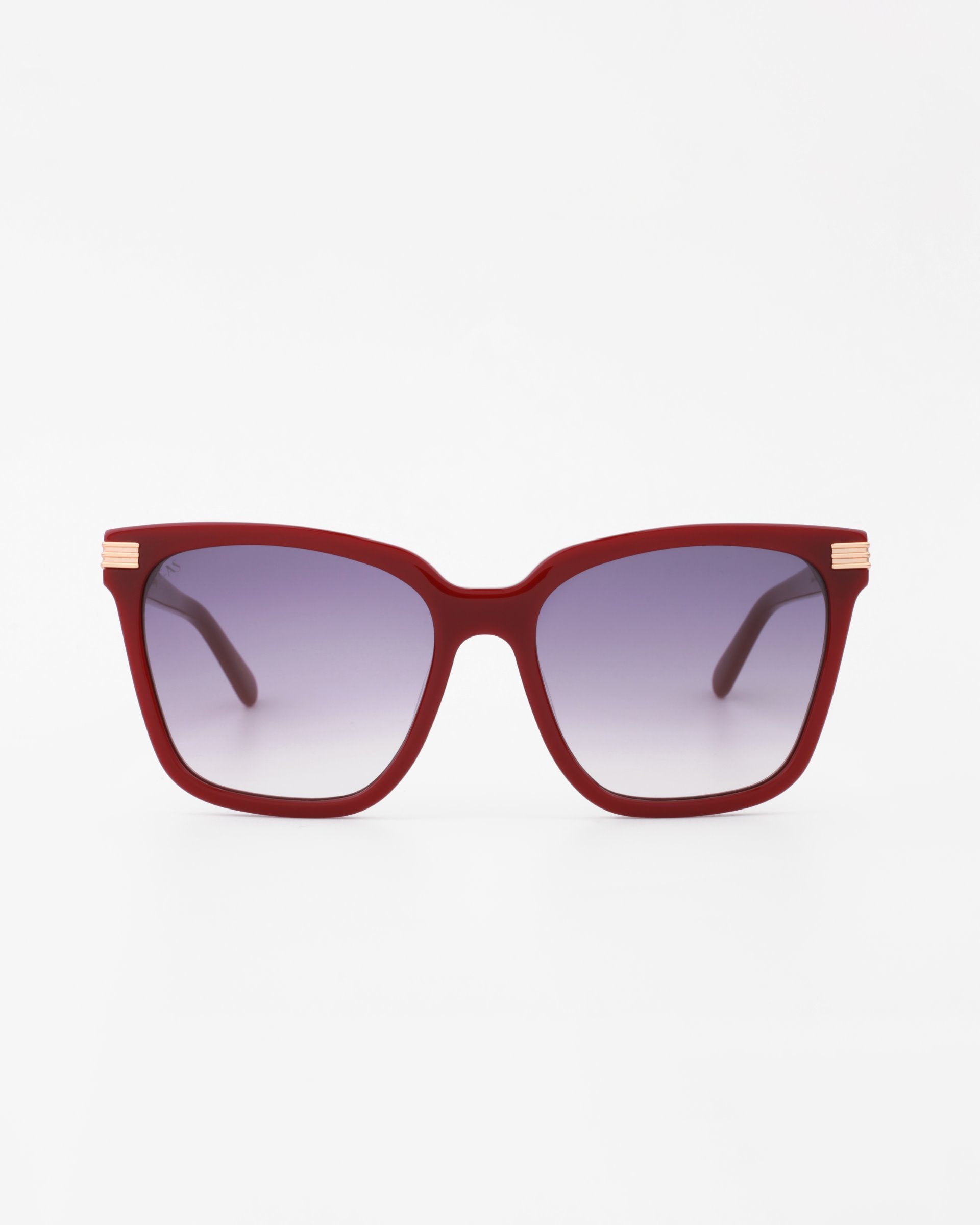 A pair of Gaia oversized square-shaped handmade acetate sunglasses by For Art's Sake® with red frames and UV-protected gradient lenses. The lenses transition from a dark tint at the top to a lighter tint at the bottom. The temples, featuring 18-karat gold-plated accents near the hinges, add a touch of luxury. The background is white.