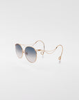 For Art's Sake® Birthday Cake-Blue sunglasses feature gold frames, blue gradient lenses, and looping temples—displayed on a plain white background and paired with handmade earrings for a distinctive style statement.