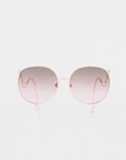 The Birthday Cake-Blue sunglasses by For Art's Sake® feature thin rose gold metal frames, pink gradient lenses, and matching rose gold earpieces. Shown against a white background—pair with faux pearl earrings for a chic look.