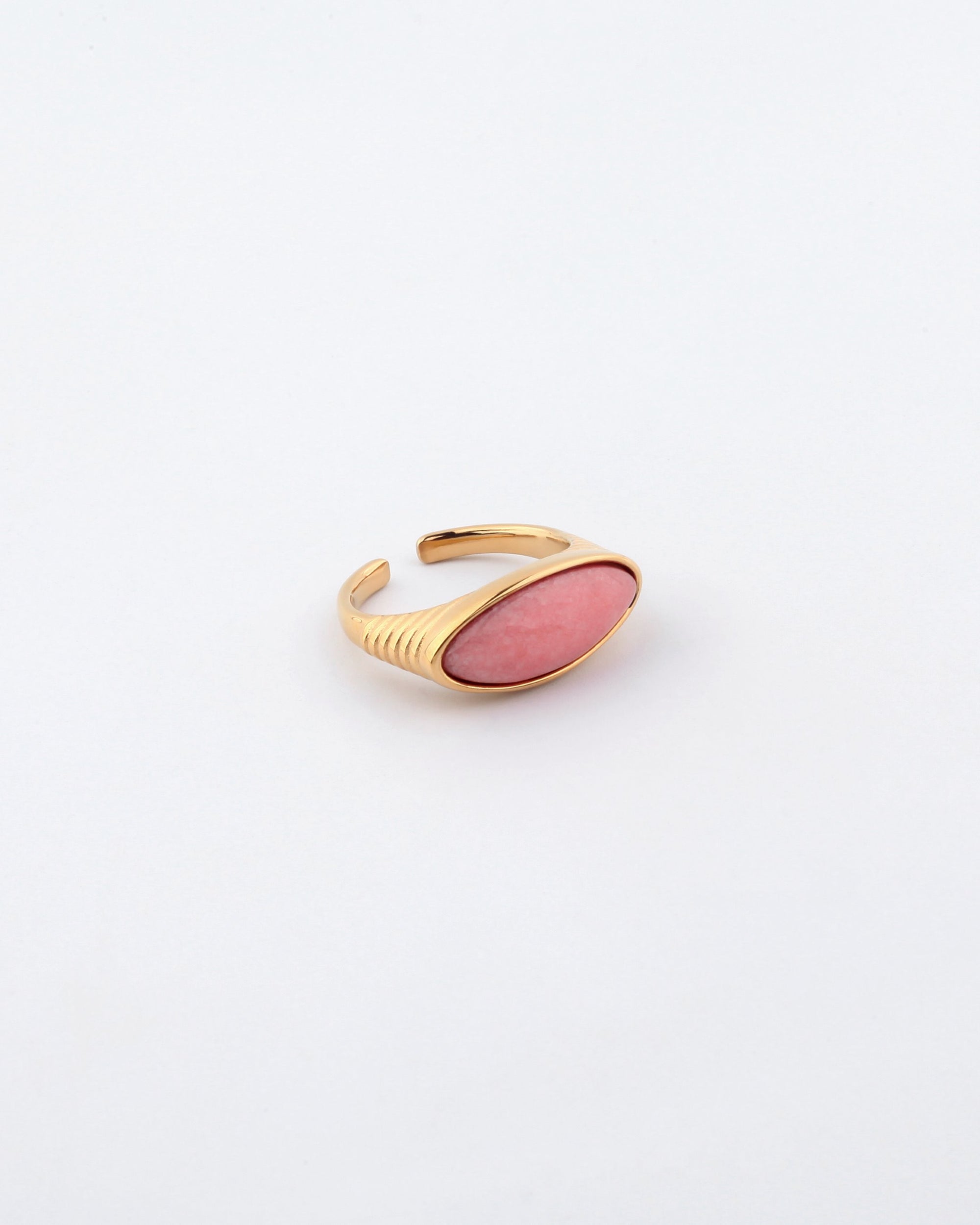 Introducing the Enza Ring by For Art's Sake®: a gold-plated stainless steel piece featuring a pink, oval-shaped stone setting. The band is adjustable with a smooth, polished enamel finish. Displayed on a plain white background, this ring exudes elegance and versatility.