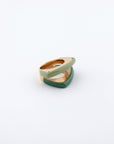 A photograph of the For Art's Sake® Delta Ring, showcasing two overlapping geometric rings. The upper ring features a pale green color and a smooth surface, while the lower ring boasts a bold splash of deep green. Both rings display a unique layered design, rounded and modern against a plain white background.