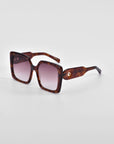 A pair of oversized soft-square sunglasses with brown tortoiseshell frames and gradient lenses. The thick frames feature classic temple round details and wide arms that taper as they extend. The **Eos** sunglasses by **For Art's Sake®** are positioned on a plain white background.