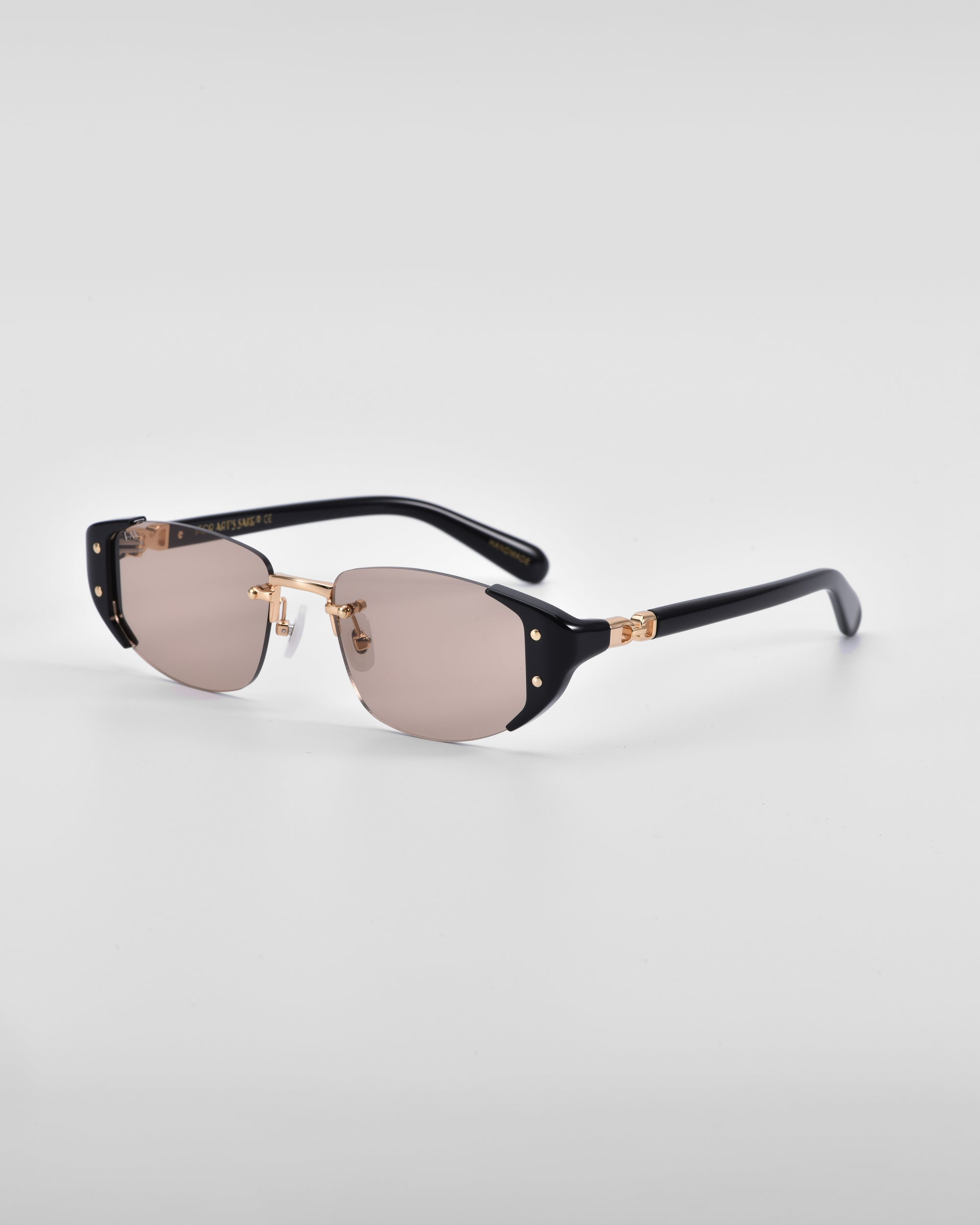 A pair of Harbour sunglasses by For Art's Sake® with 18 karat gold accents, dark black frames, and slightly tinted lenses. The temples feature retro-inspired gold details near the hinges. Set against a plain white background, these sunglasses highlight a sleek, modern design.
