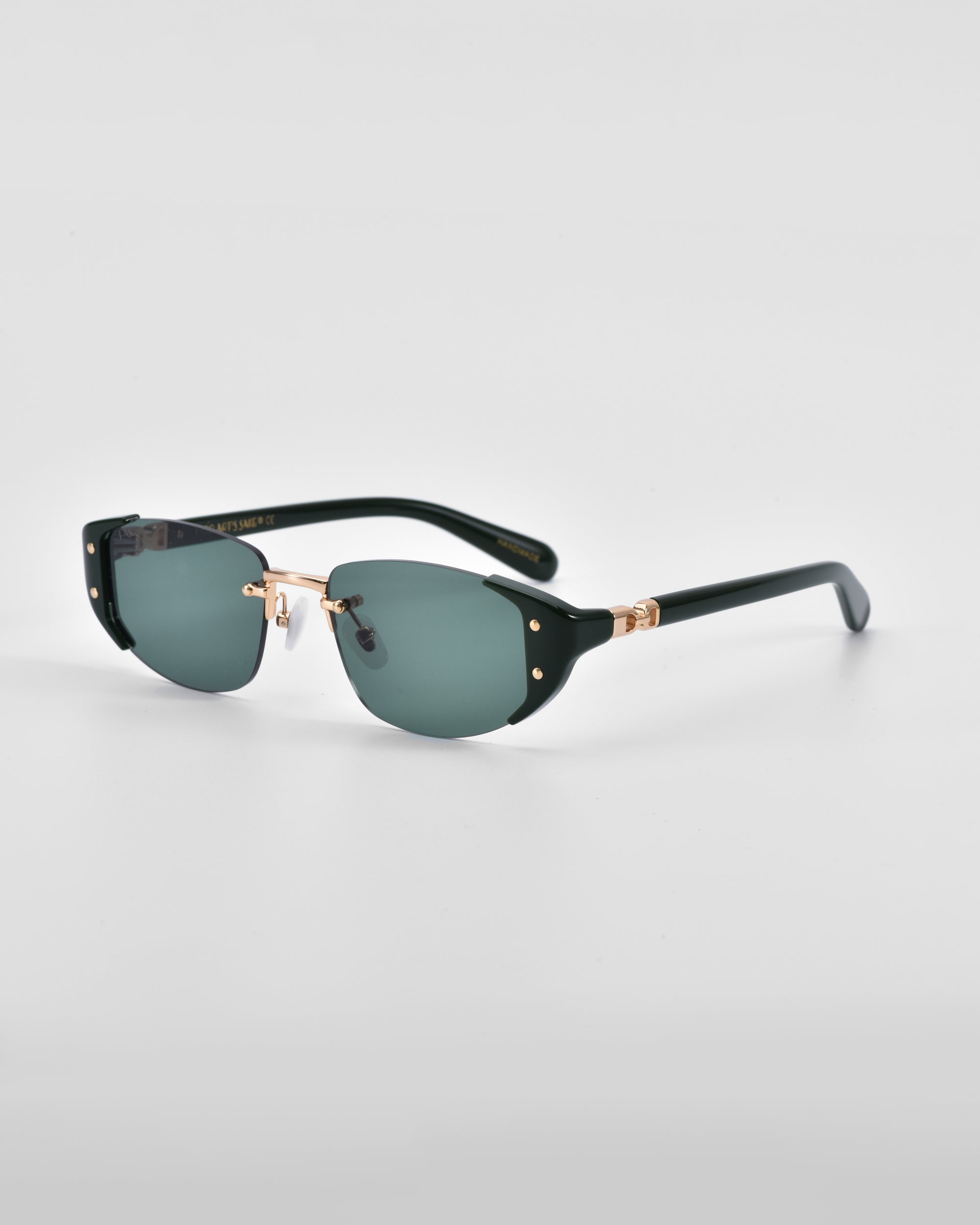 A pair of For Art's Sake® Harbour sunglasses featuring dark green lenses, black rims, and 18 karat gold plating on the hinges and nose bridge. These retro-inspired sunglasses are set against a plain light gray background.
