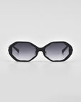 A pair of black octagonal Lotus sunglasses by For Art's Sake® with gray-tinted lenses set against a white background. The design is minimalist, featuring thin temples and no visible branding or adornments. Jade-stone nose pads and the clean, angular silhouette give these sunglasses a modern and stylish appearance.