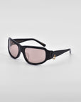 For Art's Sake® Raven sunglasses showcase a Y2K wrap design with rectangular light pink lenses and a small 18-karat gold ring accent on the side, set against a white background.
