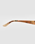 A close-up of the arm of For Art's Sake® Vincent Van Gogh (Limited Edition) cat-eye sunglasses, showcasing a floral pattern, signature details, and text, set against a plain white background.
