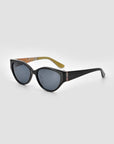 The For Art's Sake® Vincent Van Gogh sunglasses feature black cat-eye frames, dark lenses, a decorative detail, and a beige patterned inner arm—perfect collectible eyewear, displayed on a light gray background.