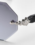 Close-up of For Art's Sake® Haze sunglasses shows octagonal light blue lenses with faceted edges. The black temples boast a unique silver hinge resembling stacked cubes, set against a plain white background to highlight the stylish design.
