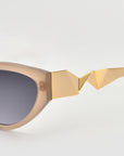 A close-up of For Art's Sake® Unfold sunglasses shows thick beige frames, dark lenses, and an angular gold accent on the temple for a modern, stylish look.