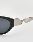 A close-up of For Art’s Sake® Unfold sunglasses, featuring angular silver detailing on the pleated temple, shown against a plain white background.