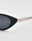 Close-up of the For Art's Sake® Slash cat-eye sunglasses, inspired by Lucio Fontana, featuring black frames, dark lenses, and silver metallic arms, set against a plain light background.