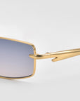 Close-up of For Art's Sake® Lucio sunglasses: sleek rectangular gold frames, gradient blue-tinted lenses, and shiny gold temples, set against a plain light gray background.